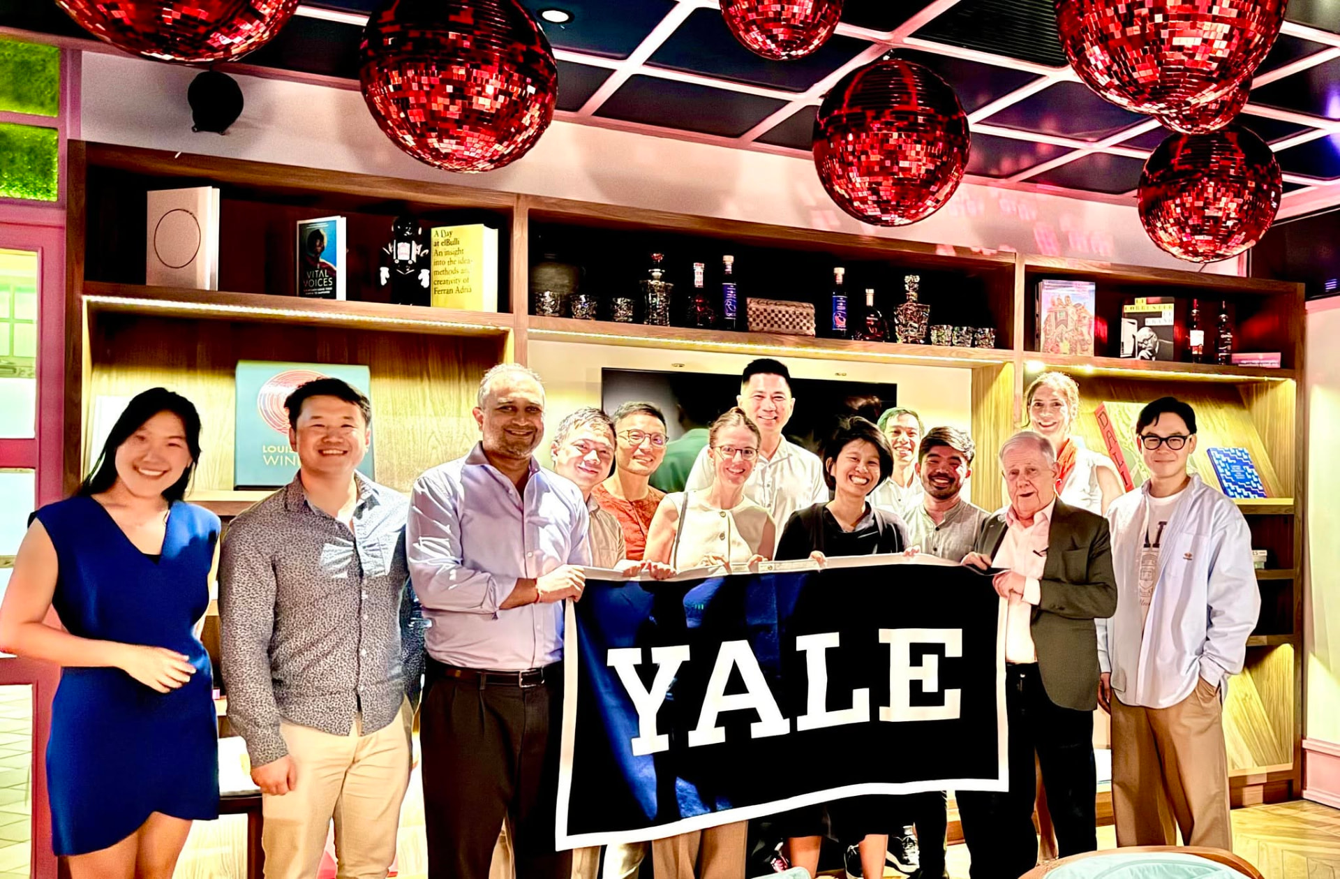 Yale Club of Singapore members holding a Yale banner at a social gathering